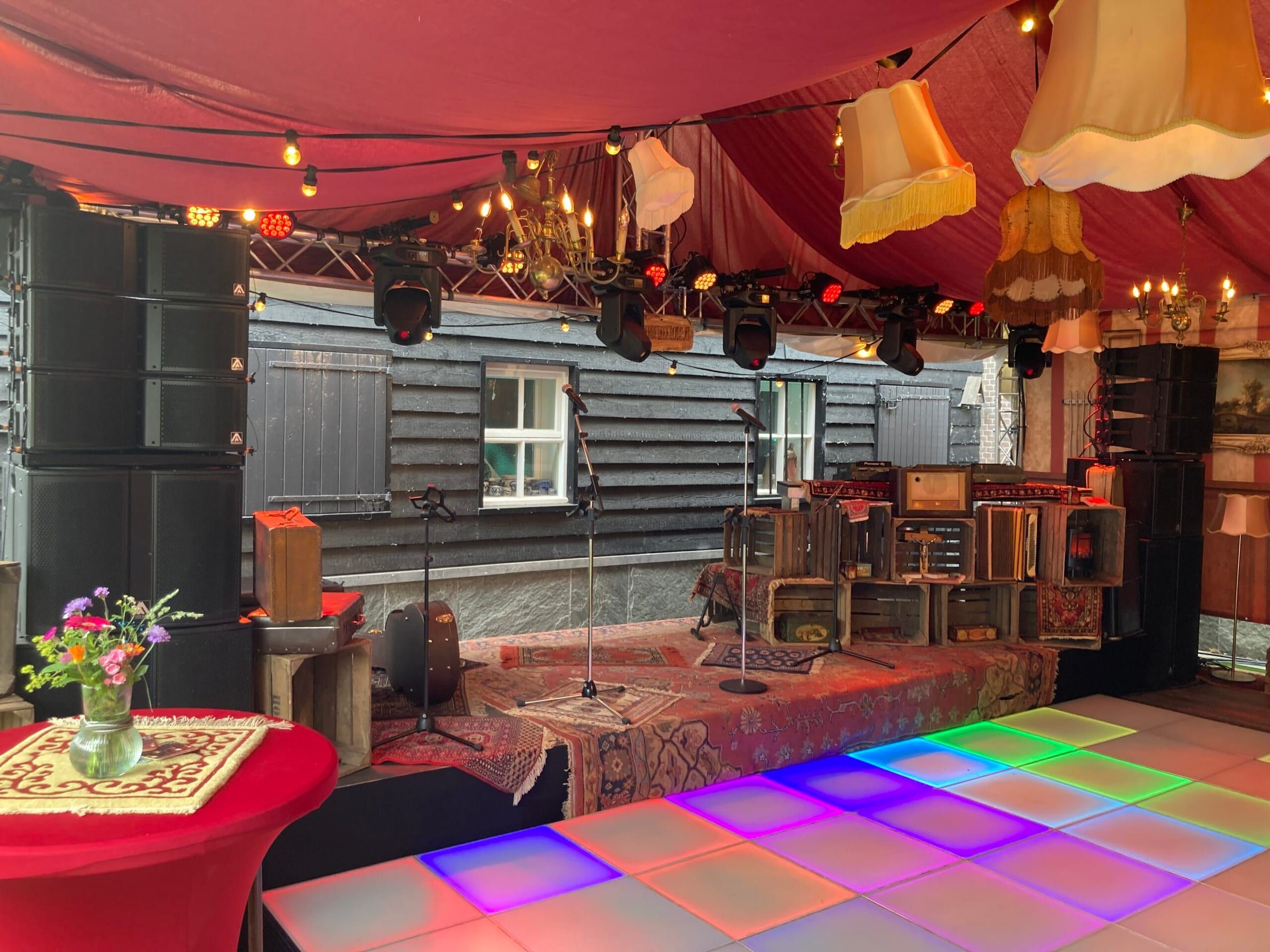 Podium met speakers, lichtset aan truss en een verlichte dansvloer