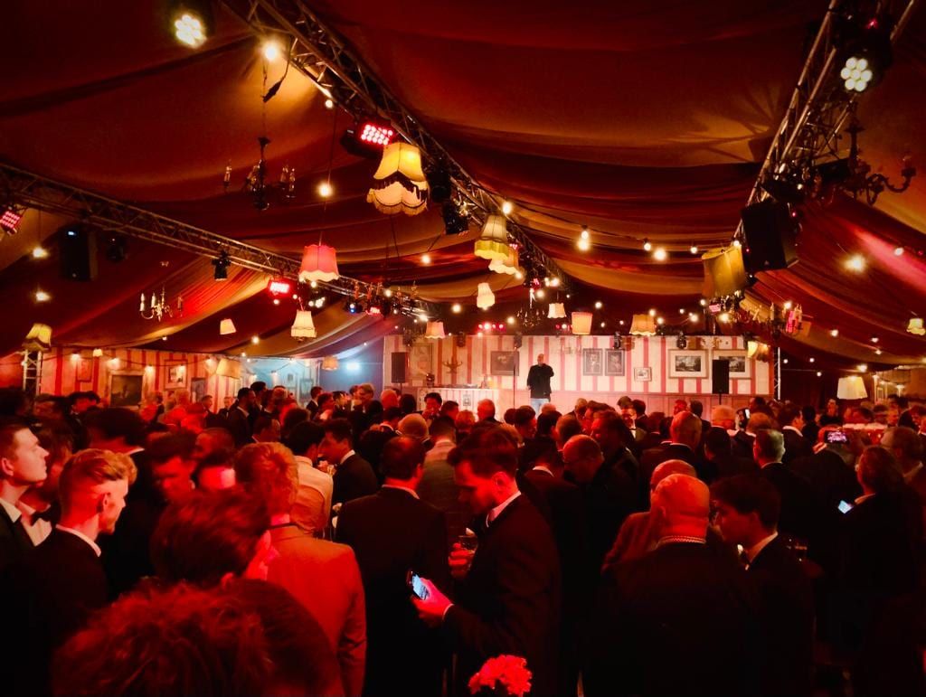 Volle zaal met feestgangers onder lampjes, schemerlampen en truss
